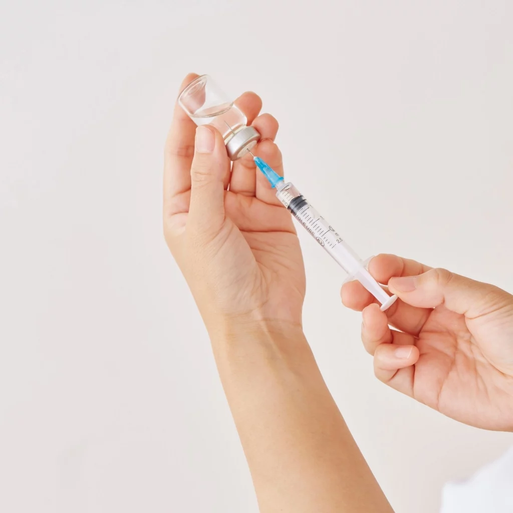 Hands drawing anti-wrinkle injectable from vial at Etica Clinic London