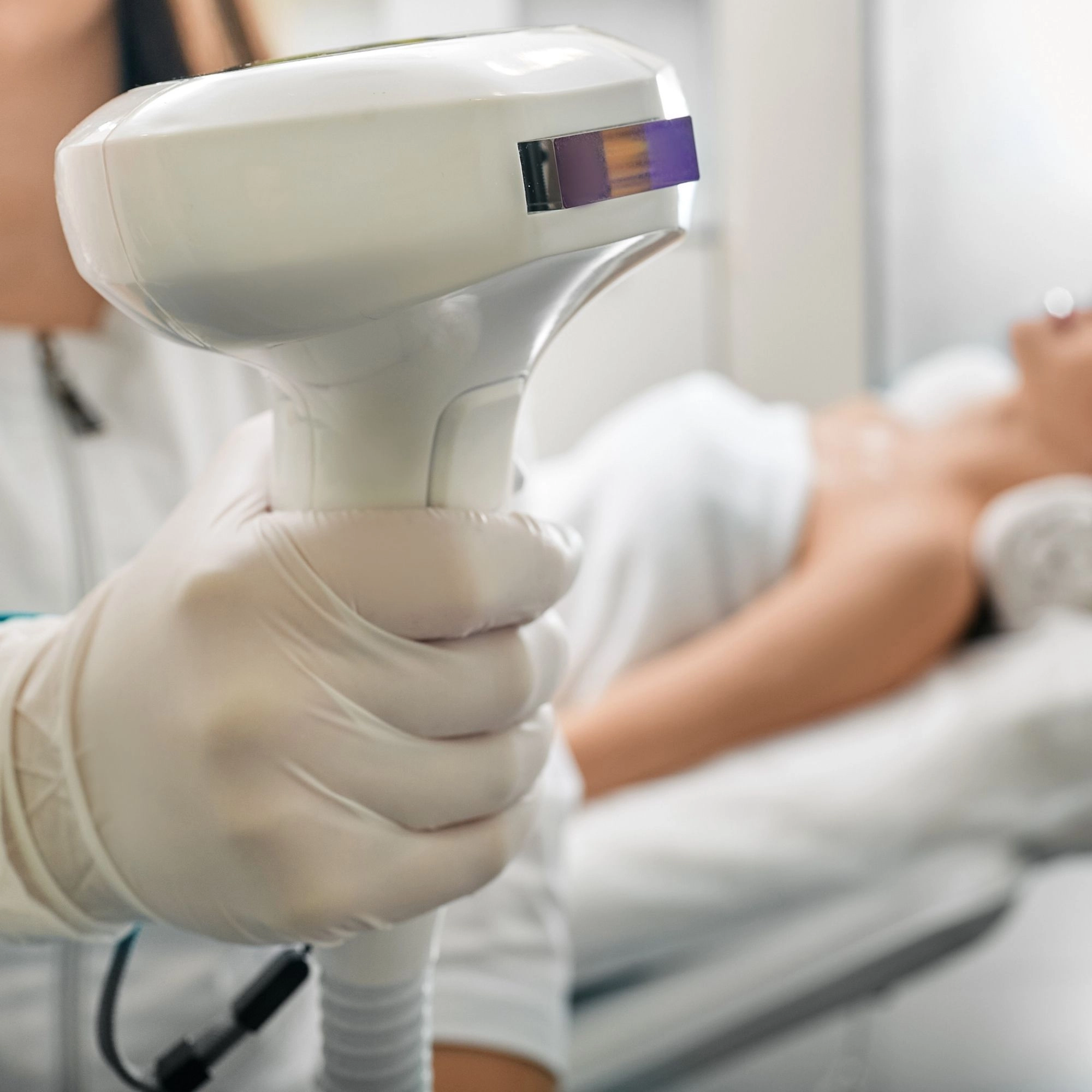 Gloved hand holding Lumecca IPL handpiece during luxury facial treatment at Etica Clinic.