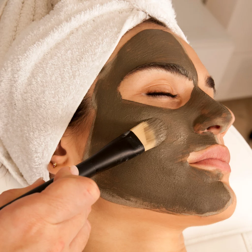 Woman receiving a luxurious green clay facial mask at Etica Clinic